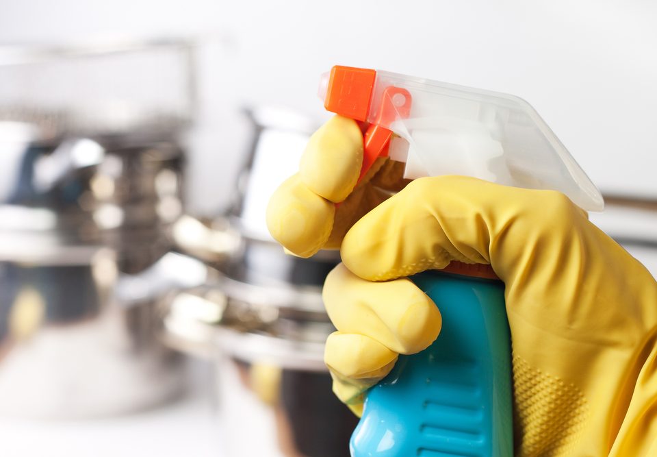 hand in protective glove holding spray. cleaning a kitchen concept